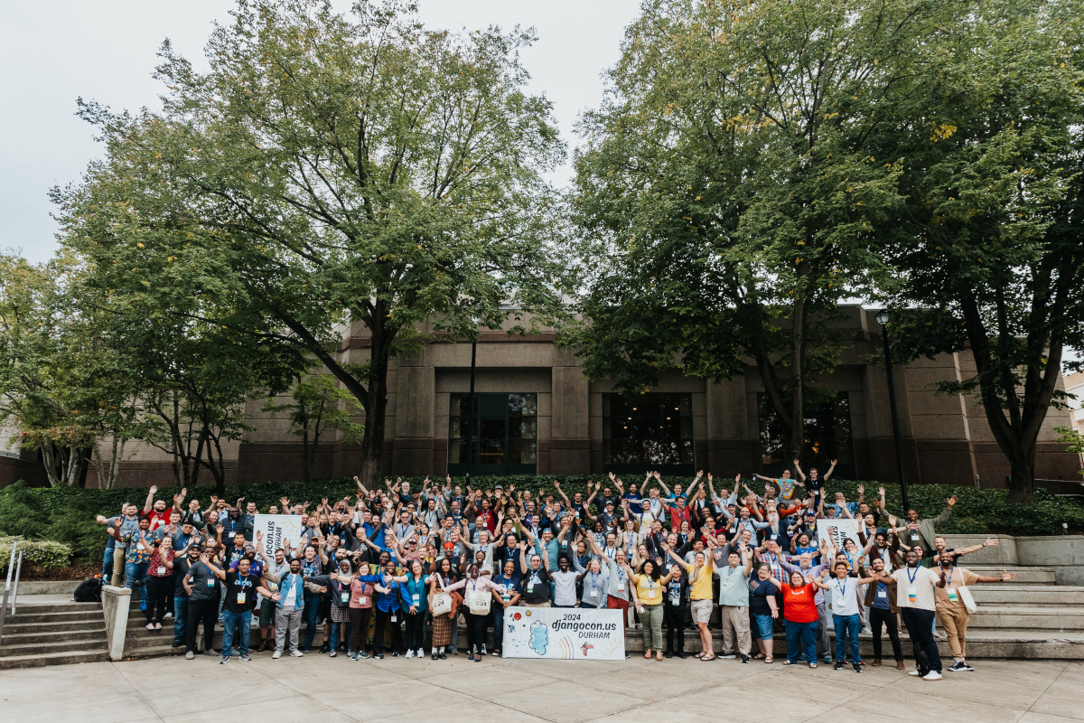 The DjangoCon US 2024 attendees welcoming everyone to Durham, NC! It's hundreds of people standing with their arms extended outwards.